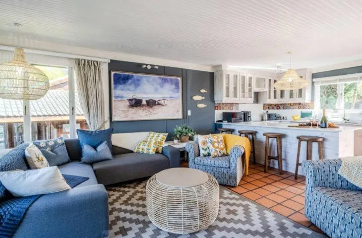 Open-plan lounge with blue sofa, TV, and kitchen visible in background