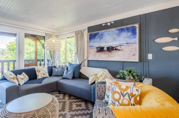 Modern lounge with blue sectional sofa, coastal artwork, and garden views