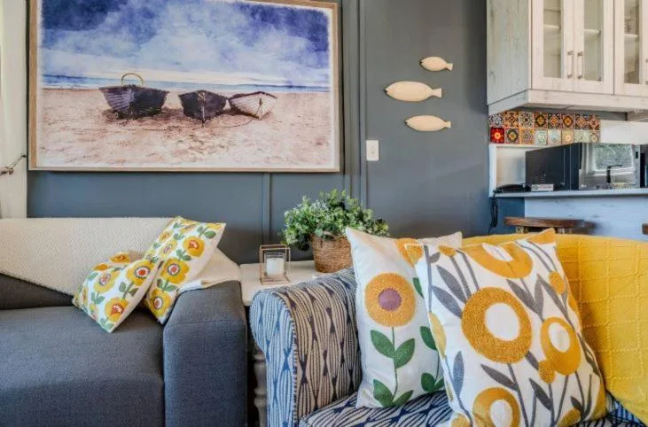 Coastal-themed lounge with sunflower pillows and beach artwork
