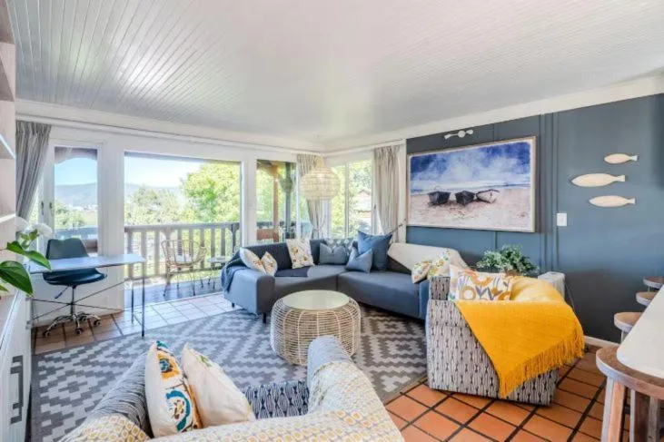 Spacious lounge with blue sofa, yellow accent chair, and ocean view artwork