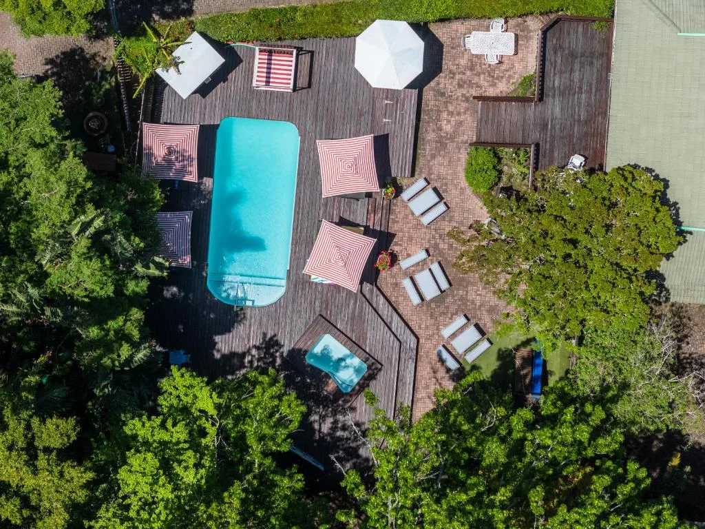 Aerial view of turquoise swimming pool surrounded by wooden deck and lounge chairs