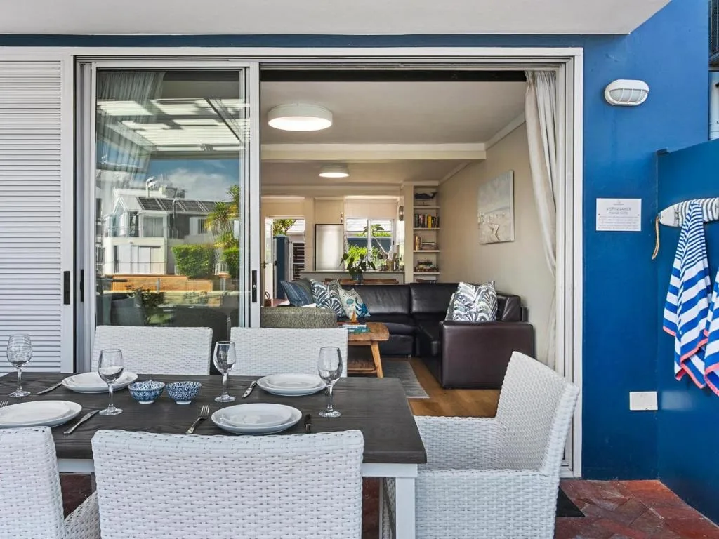 Outdoor dining area with table and chairs opening to interior lounge space
