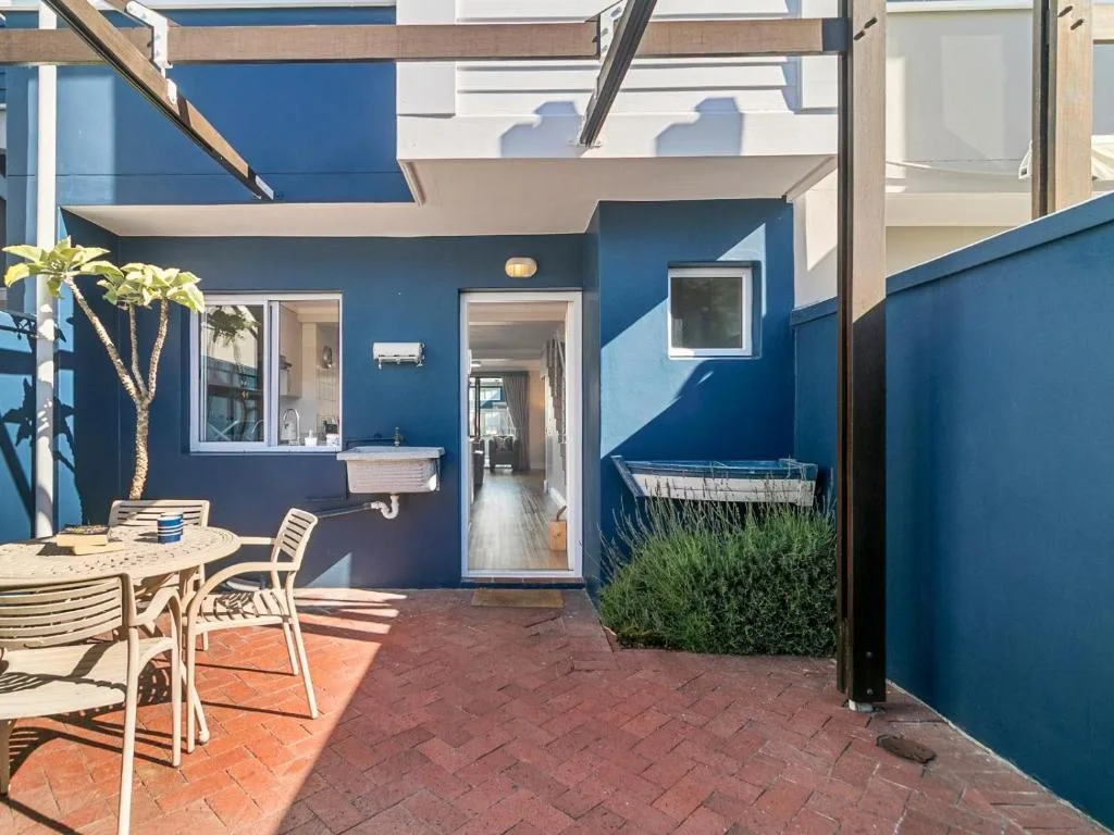 Blue-walled patio with dining table, chairs, and potted palm tree