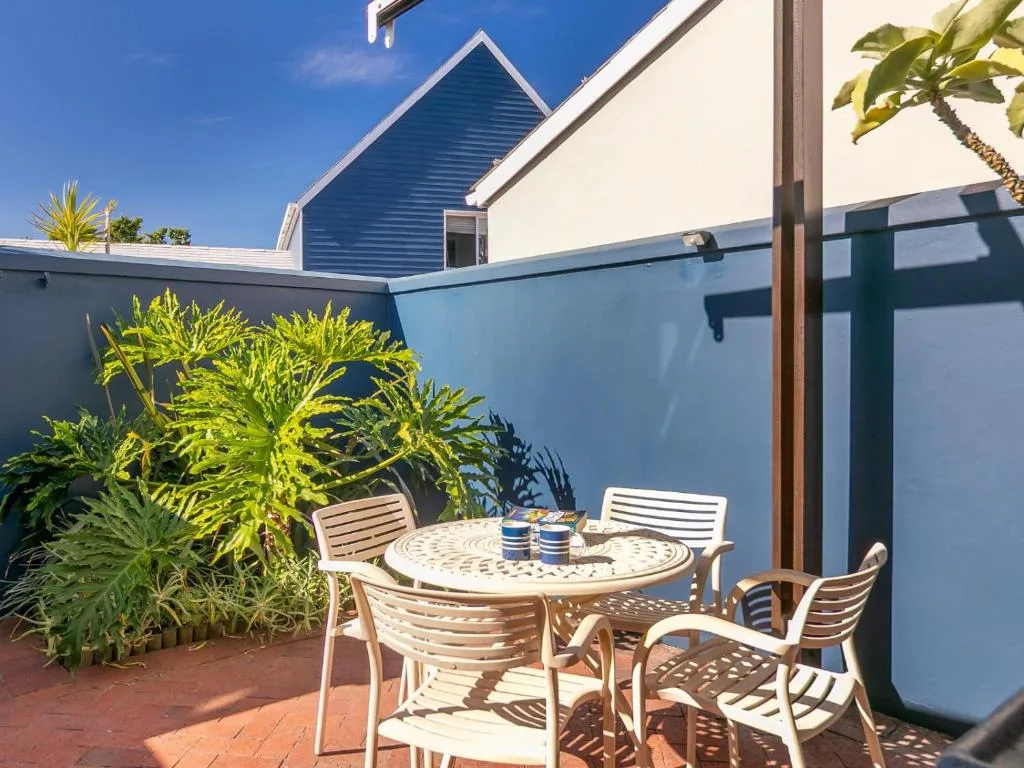 Outdoor patio with round table, chairs, and tropical plants
