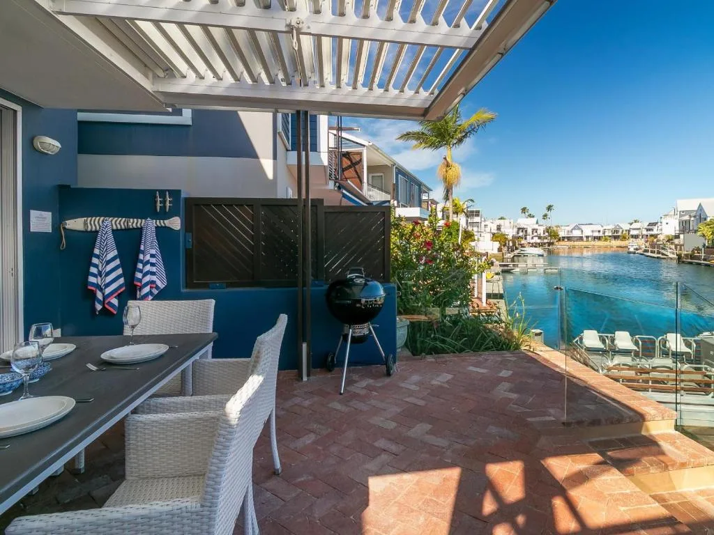 Waterfront deck with dining table, braai grill, and lagoon views