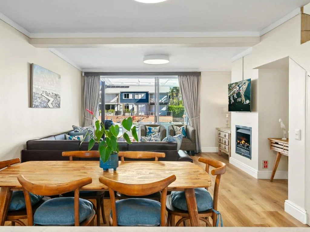 Open-plan dining area with wooden table and blue-cushioned chairs overlooking lounge