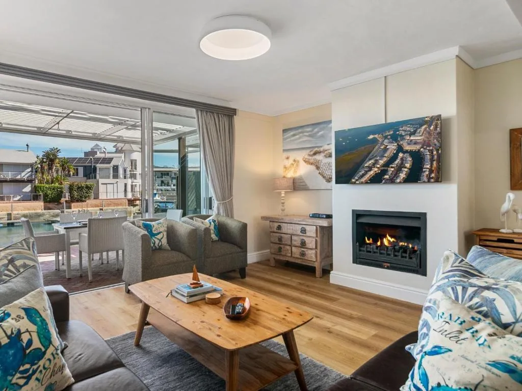 Spacious lounge with fireplace, sofas, wooden table, and ocean views through glass doors