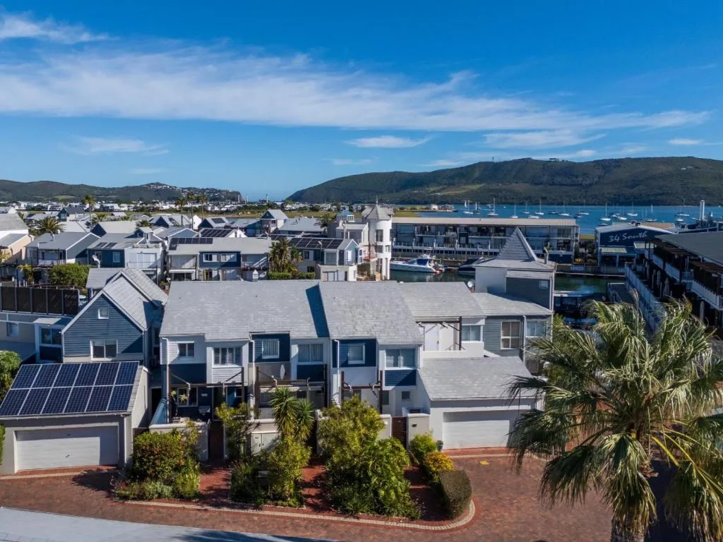 Aerial view of beachfront villa community with harbor and mountains beyond