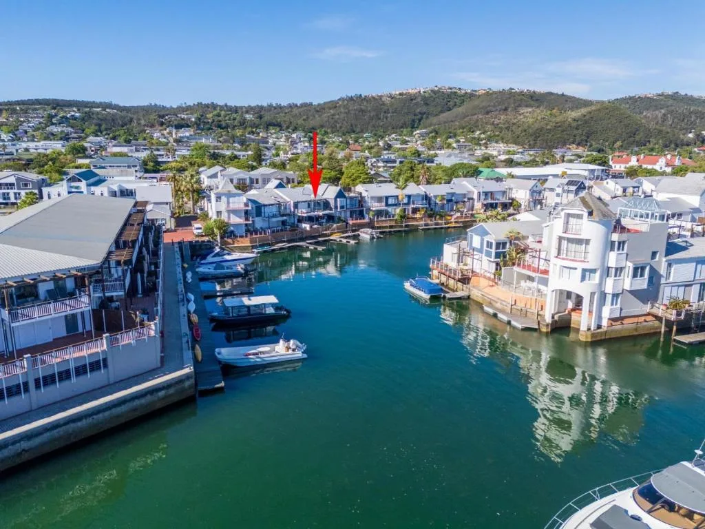 Aerial view of waterfront properties with lagoon, moored boats, and forested hills
