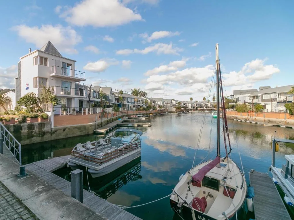 Waterfront view of modern villa with lagoon, boats, and blue sky
