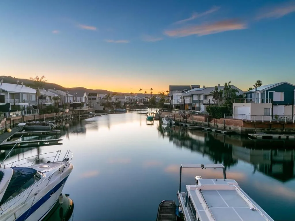 Serene waterfront sunset view with moored boats and residential properties lining the canal