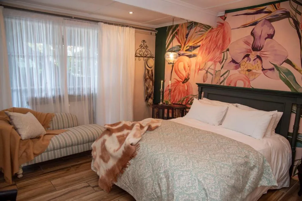 Elegant bedroom with queen bed, floral artwork, and lounge seating area
