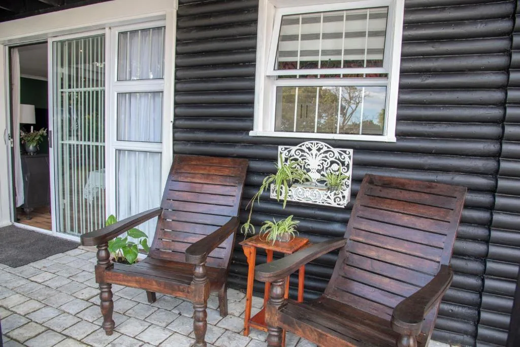 Wooden lounge chairs on paved patio beside corrugated iron building
