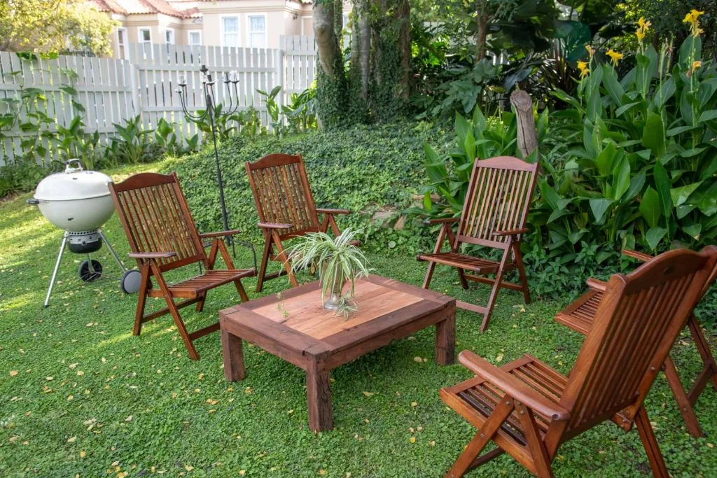 Garden seating area with wooden chairs, table, and braai grill