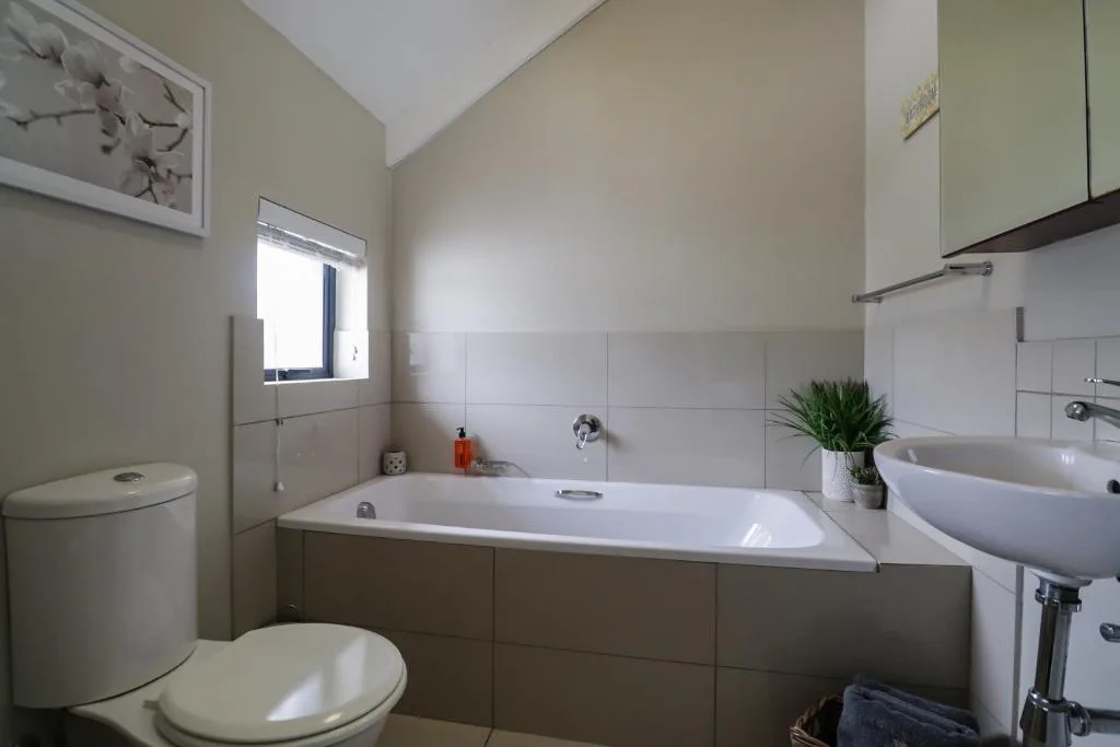 Modern bathroom with bathtub, toilet, vanity sink and window