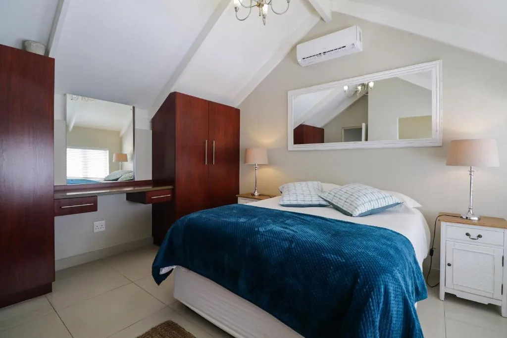Spacious bedroom with queen bed, dark wood wardrobe, and ensuite vanity area