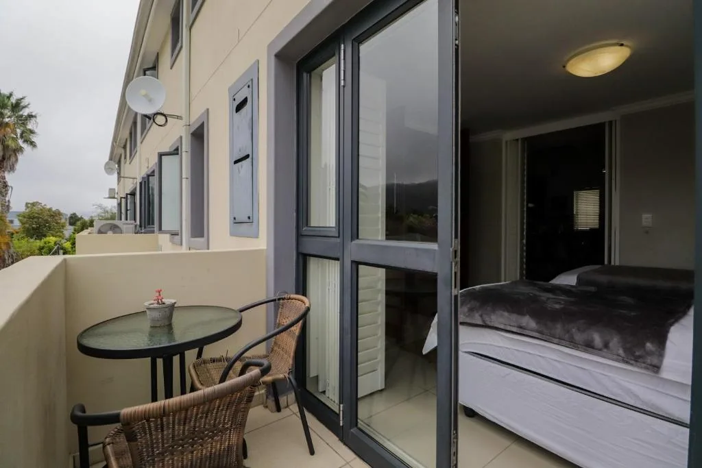 Bedroom with bed visible through open glass doors, small balcony with table