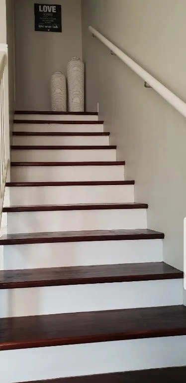 Modern staircase with dark wood treads and white risers, decorative baskets displayed