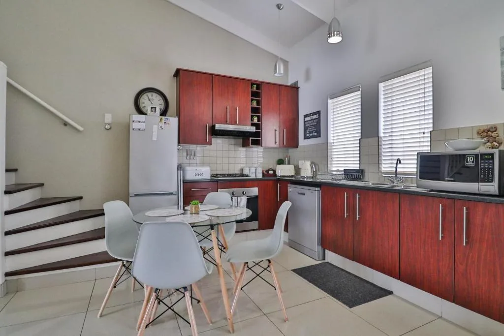 Modern kitchen with red cabinetry, stainless steel appliances, and dining table