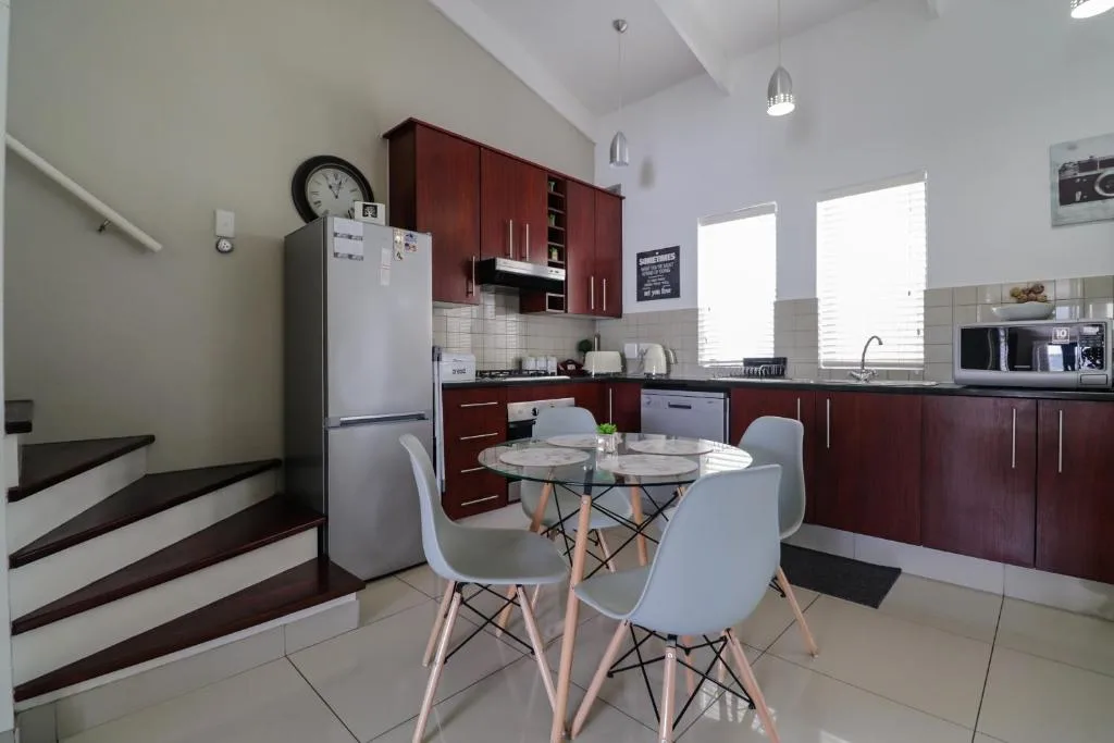Modern kitchen with burgundy cabinetry, white appliances, and dining table