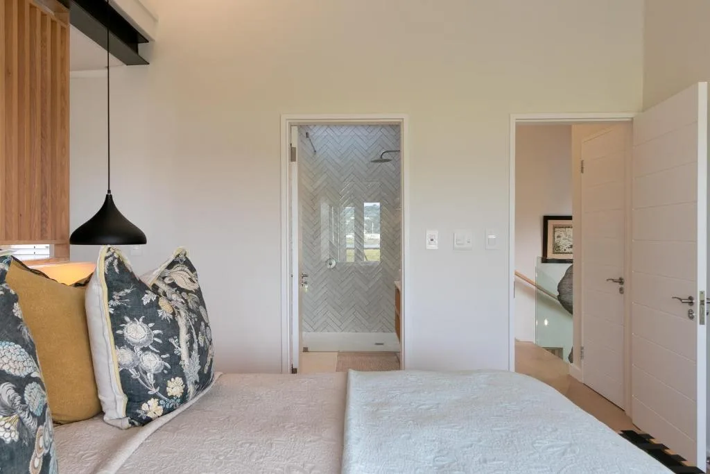 Modern bedroom with ensuite bathroom and herringbone tiled shower visible