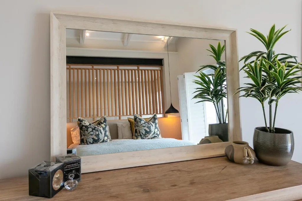 Modern bedroom with framed bed, patterned pillows, and potted plants