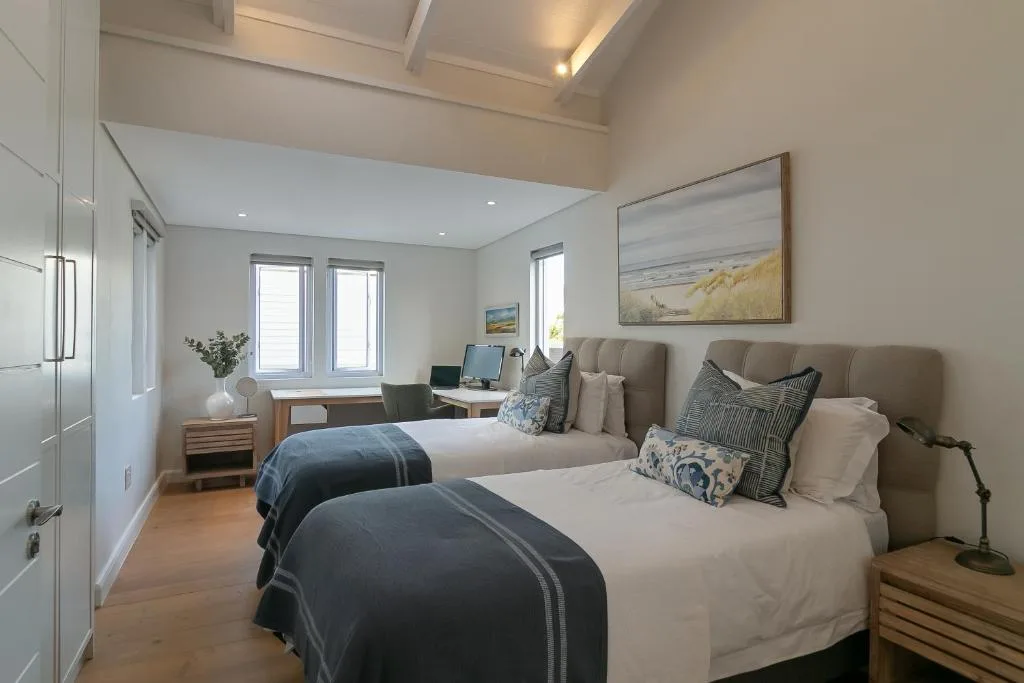 Spacious bedroom with twin beds, desk workspace, and large windows
