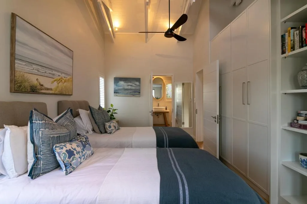 Modern bedroom with twin beds, patterned pillows, and en-suite bathroom view
