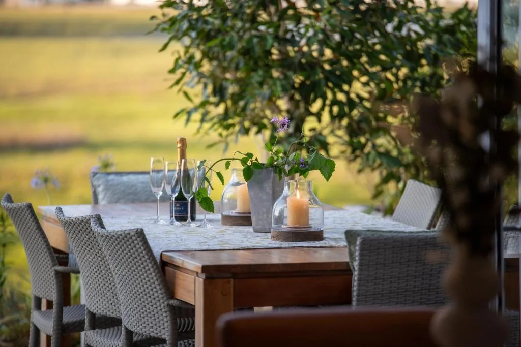 Outdoor dining table with champagne glasses overlooking lagoon views
