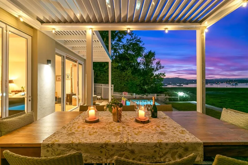 Covered patio with dining table overlooking lagoon at sunset