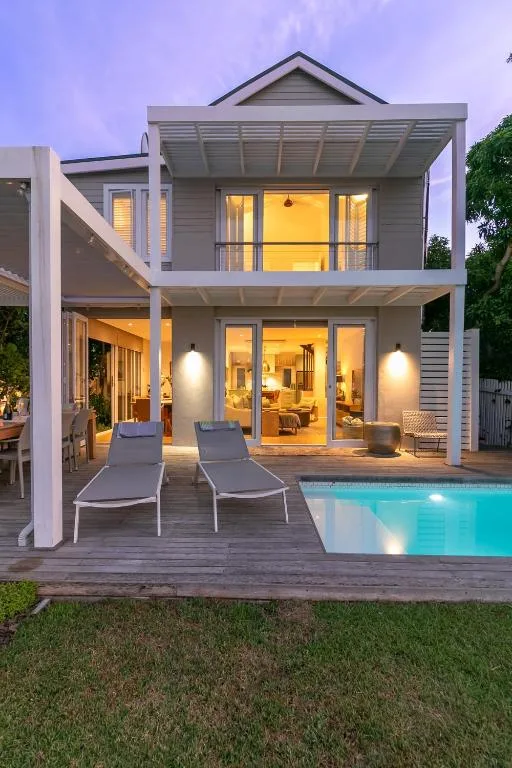 Modern two-story villa exterior with pool and illuminated interior at dusk