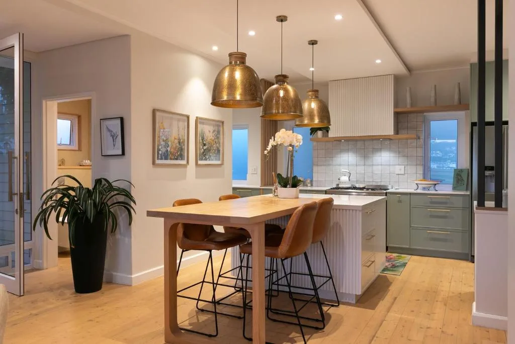 Modern kitchen with dining island, brass pendant lights, and ocean views