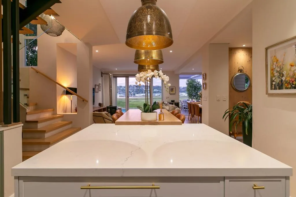 Modern white kitchen island with marble countertop and brass pendant light
