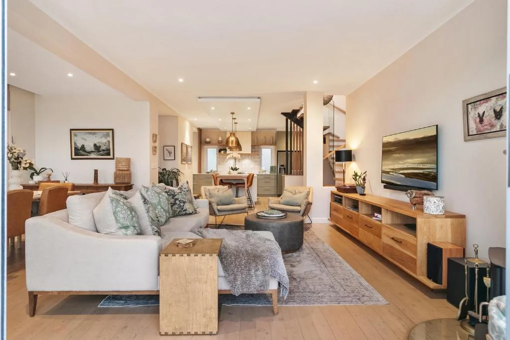 Spacious modern lounge with white sofa, wooden furniture, and flat-screen TV