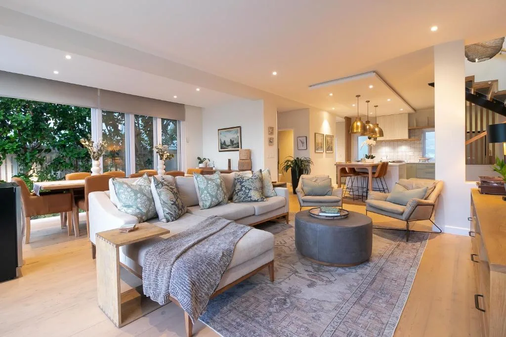 Spacious open-plan lounge with sofa, armchairs, and ottoman seating area