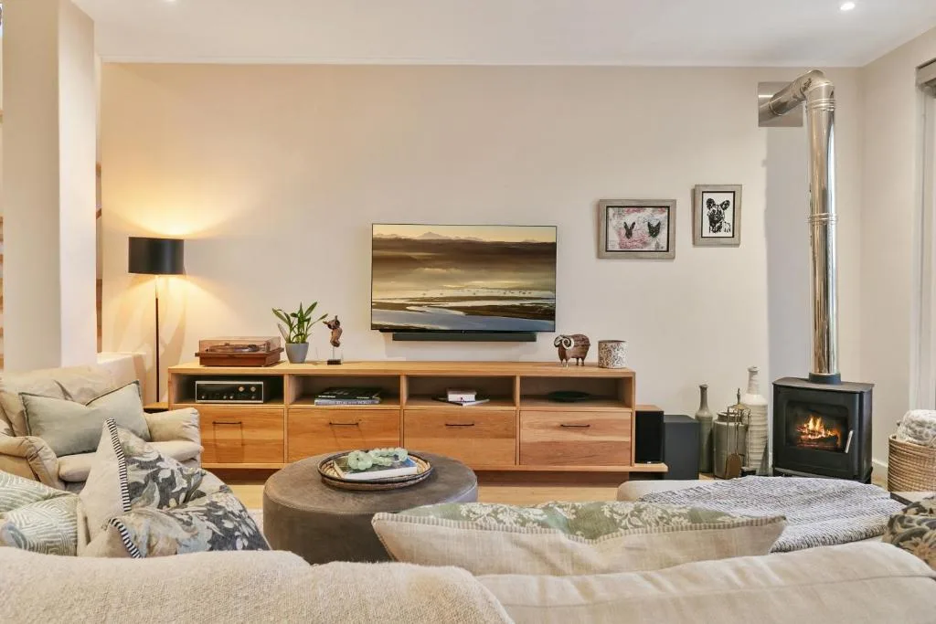 Modern lounge with cream sofas, wooden TV unit, fireplace, and warm lighting