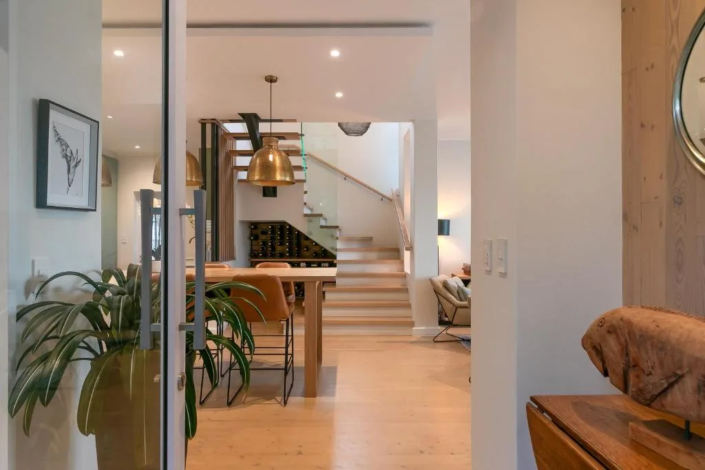 Open-plan lounge with wooden floors, pendant lighting, and staircase view