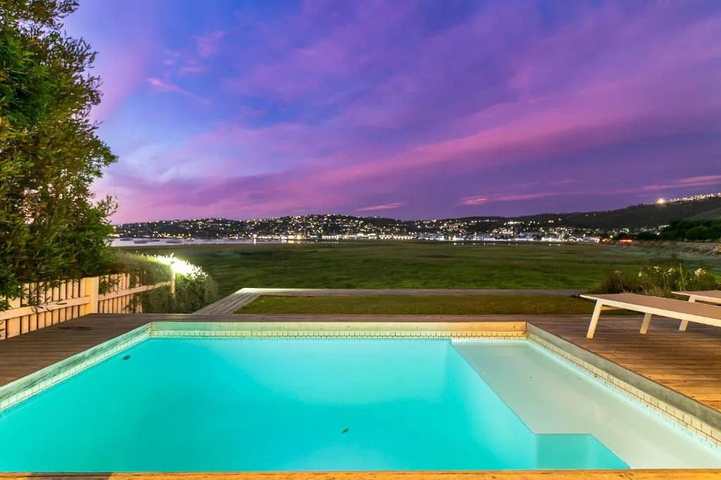Swimming pool overlooking Knysna lagoon at dusk with purple sunset sky