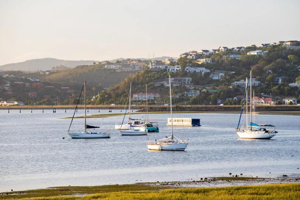 Scenic lagoon view with sailboats and hillside homes in Knysna