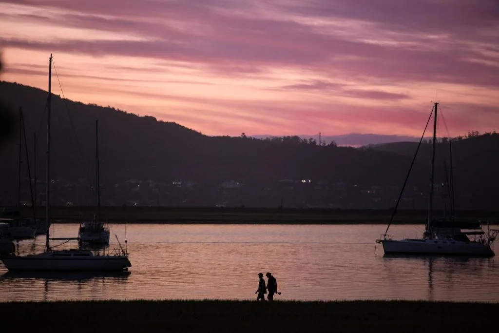 Sunset over Knysna lagoon with moored sailboats and forested hills