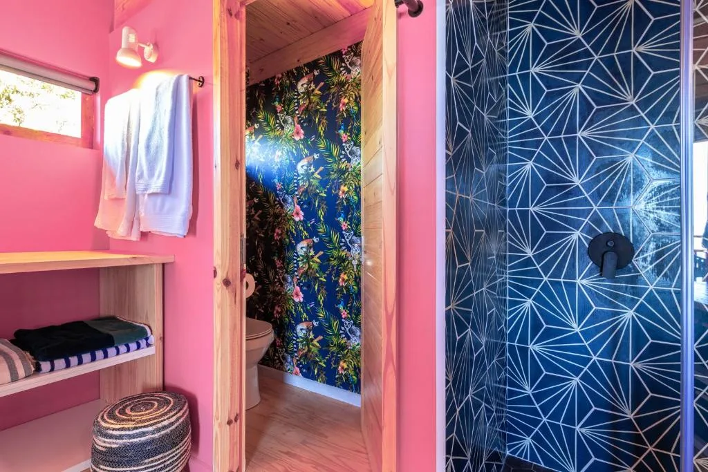 Bright pink bathroom with colorful floral wallpaper and geometric shower enclosure