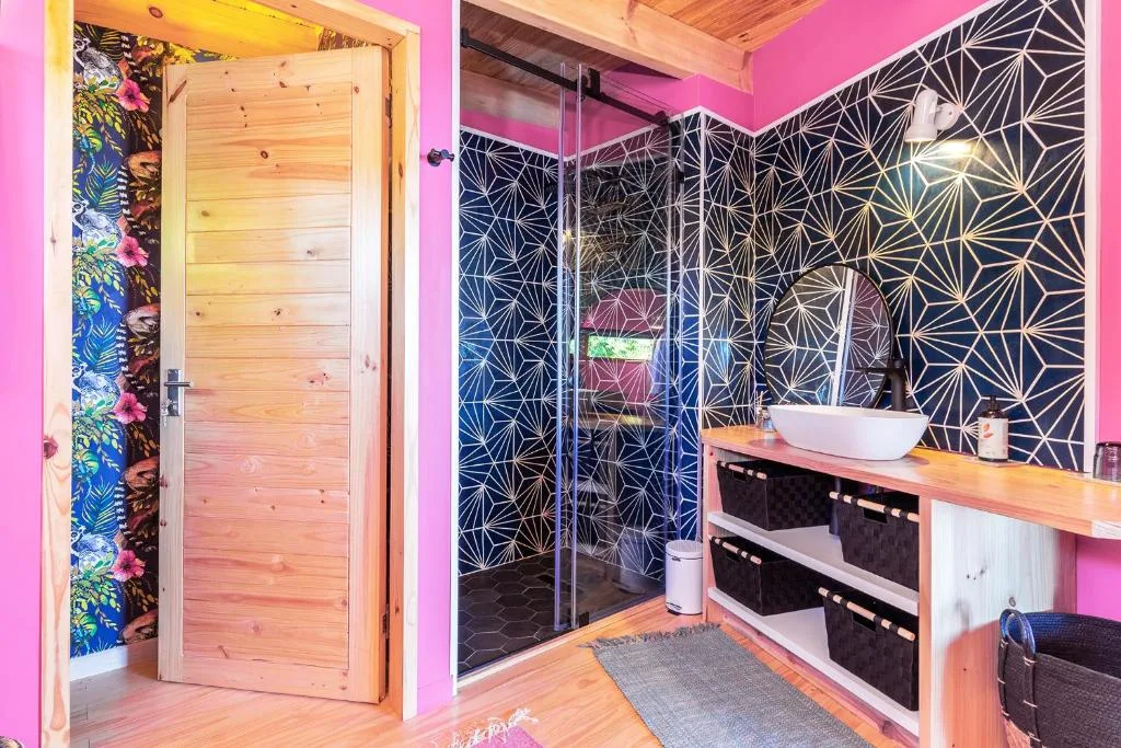 Modern bathroom with geometric patterned tiles, vessel sink, and vibrant pink walls