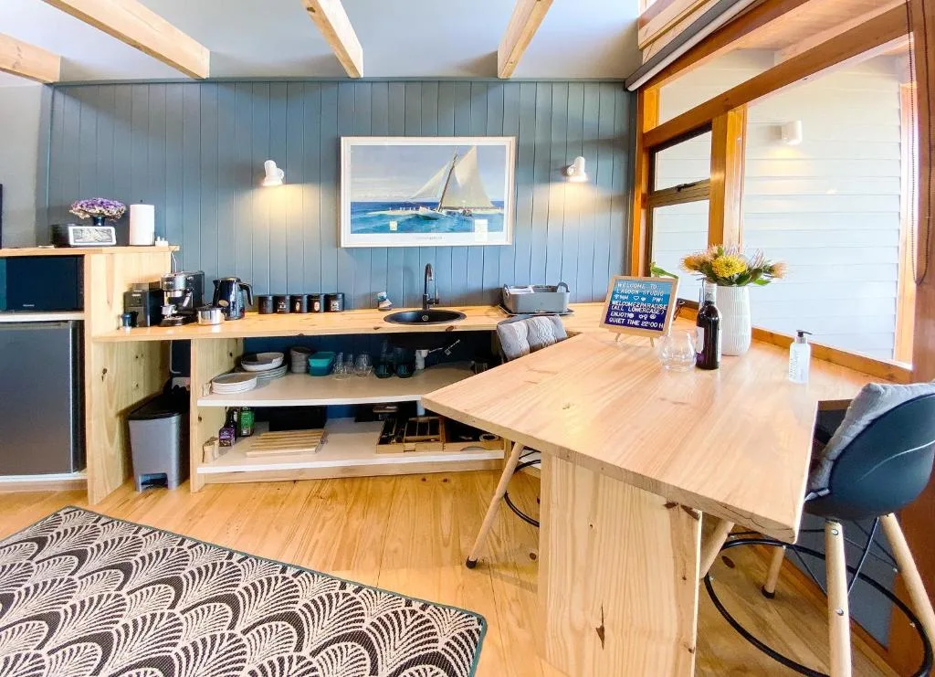 Modern kitchen with light wood cabinetry, blue walls, and open shelving