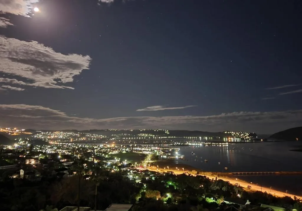 Moonlit night view of Knysna Lagoon with illuminated town and water reflections