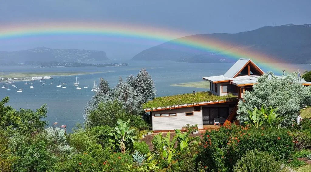 Rainbow over Knysna Lagoon with moored sailboats and surrounding mountains