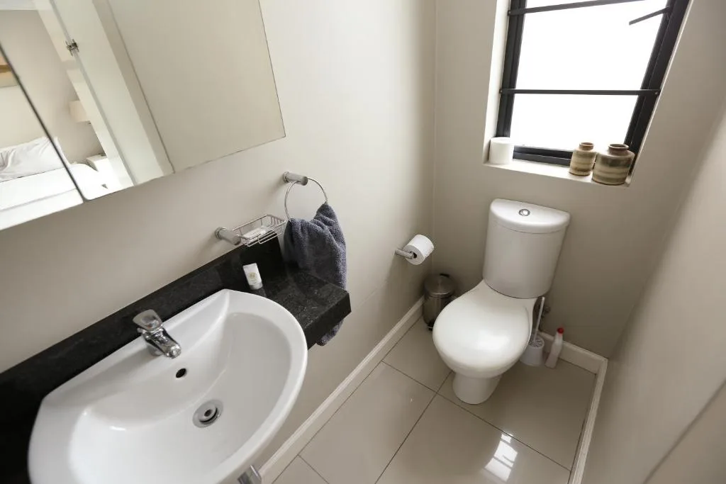Clean modern bathroom with white sink, toilet, and window overlooking the property