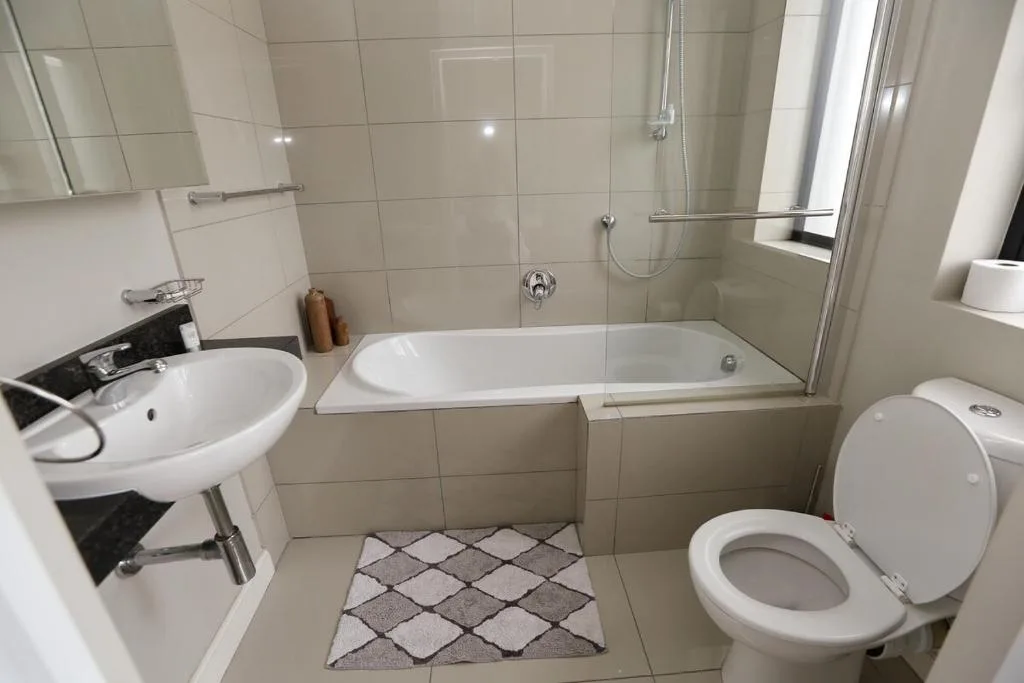 Clean bathroom with white tiles, bathtub, sink, and toilet