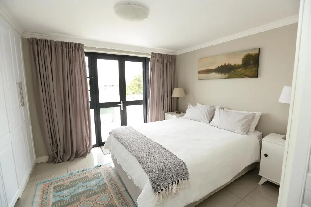 Spacious bedroom with queen bed, neutral tones, and sliding door to balcony