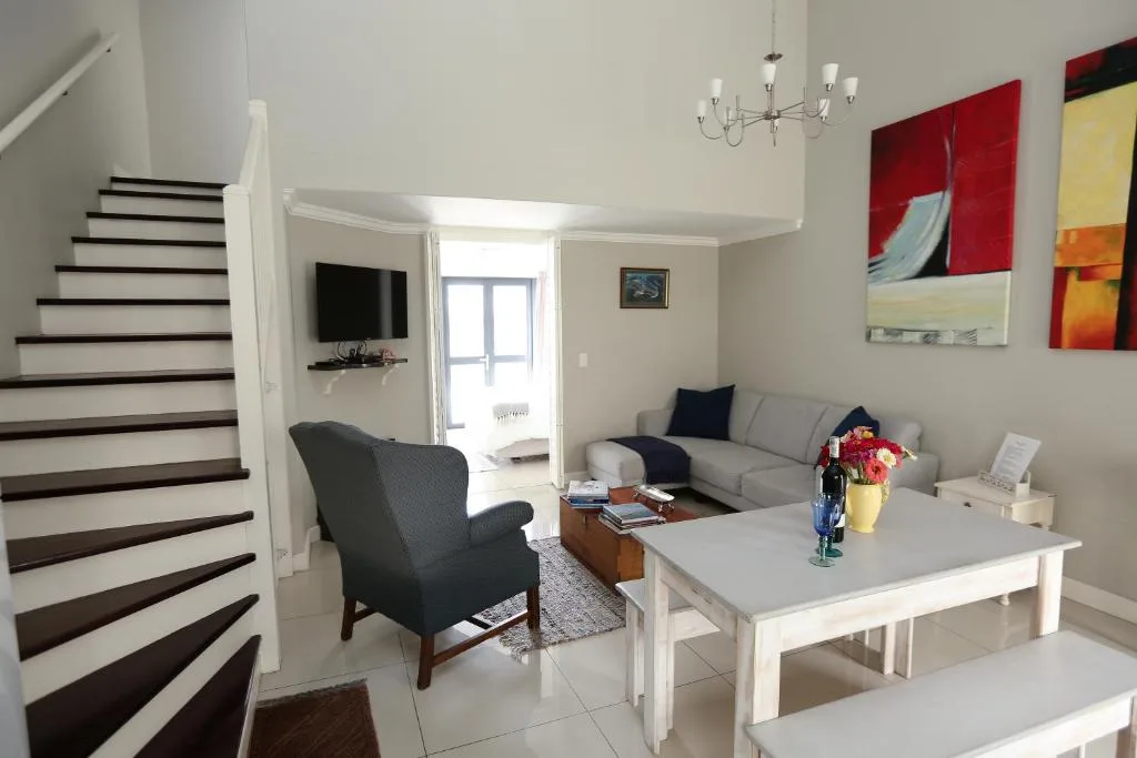 Modern living room with gray sofa, armchair, dining table, and staircase
