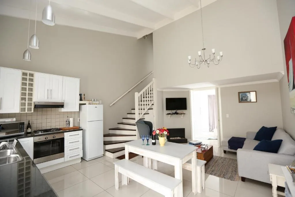 Open-plan lounge with sofa, dining table, and kitchen visible in background